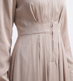 Close-up detail of a light khaki dress waistline, featuring chest pleats, a front zipper placket, and smooth luminous satin fabric texture.