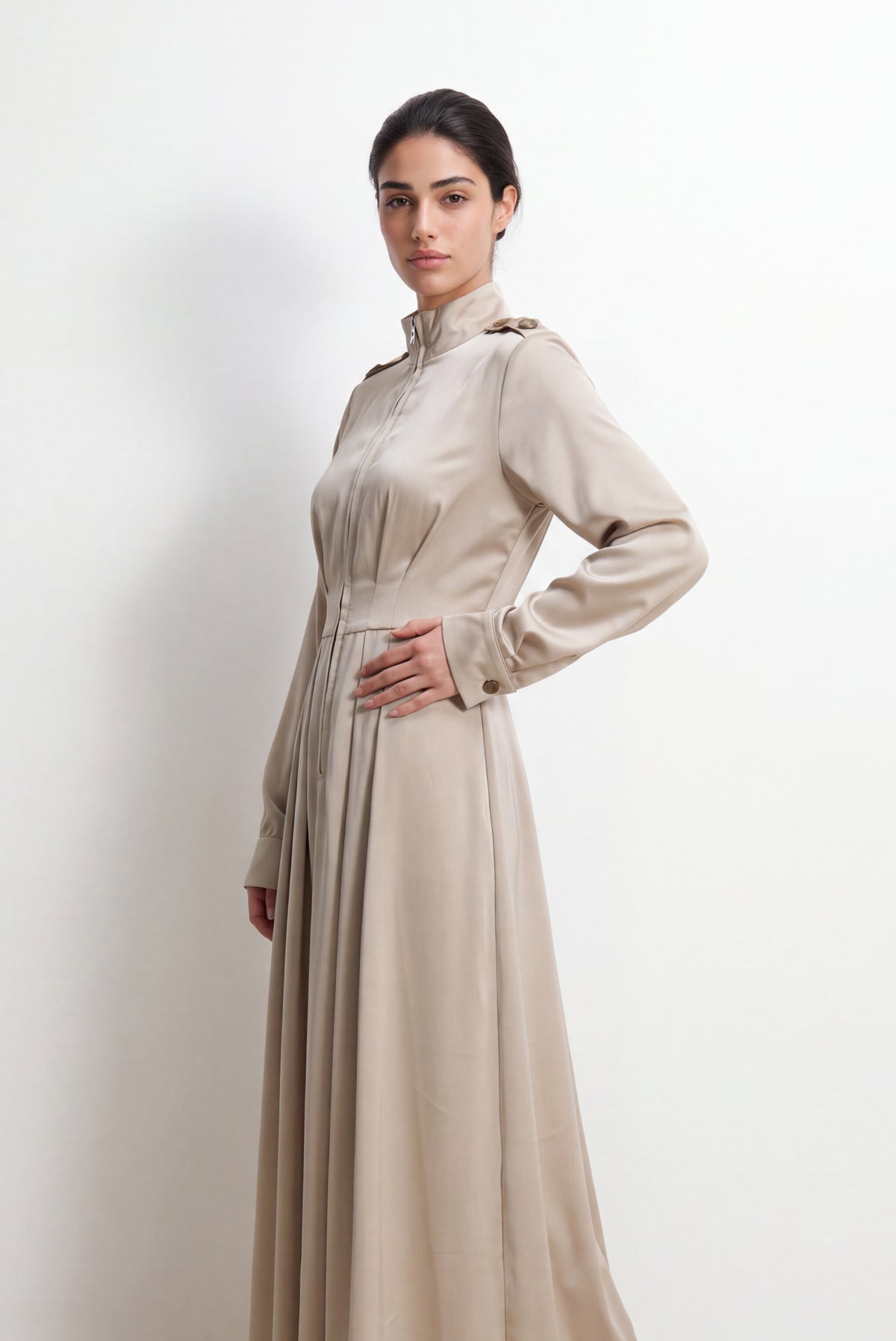 Side-angle view of a light khaki modest satin maxi dress, showing the tailored waist, long sleeves, and elegant flowing skirt.